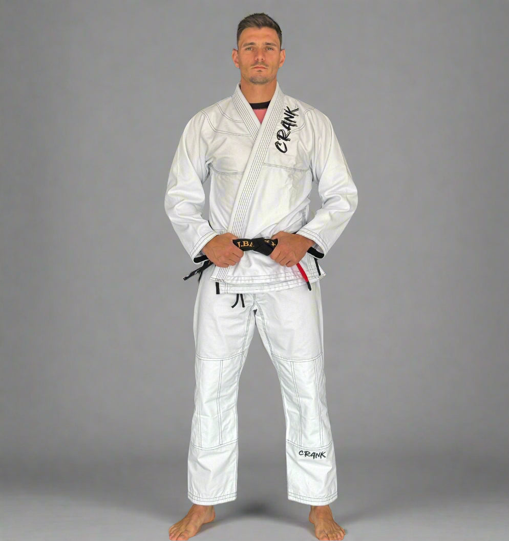 Person wearing a white martial arts uniform with 'Rena' branding against a gray wall.