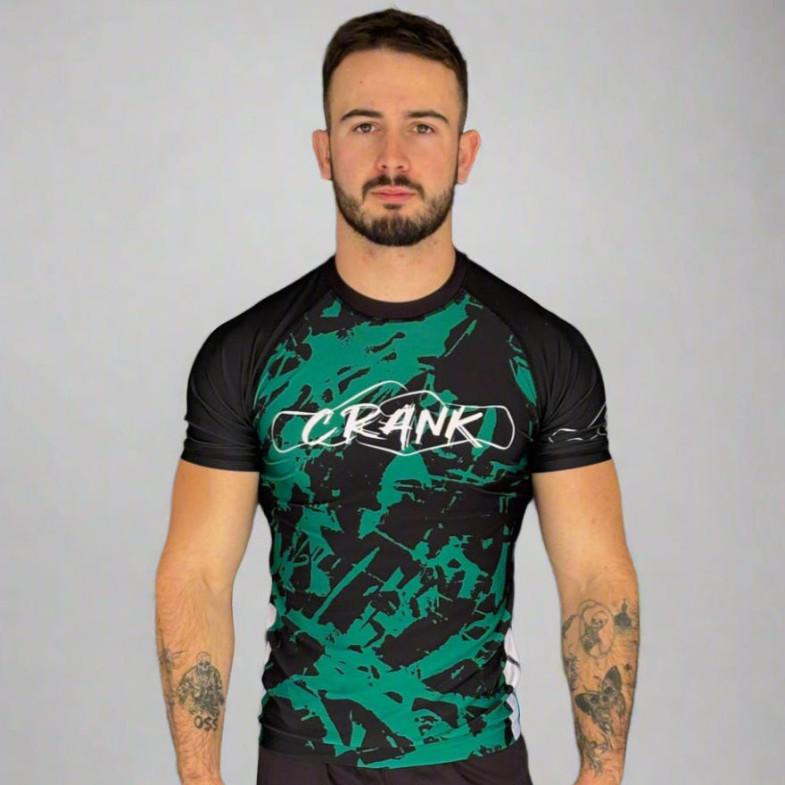 Man wearing a black and green athletic outfit with 'CRANK' branding against a gray background
