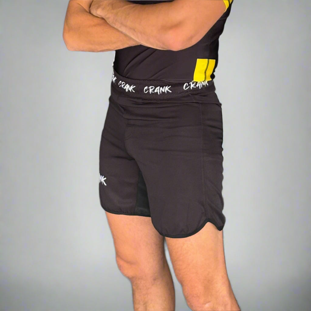Man wearing a black and yellow athletic outfit with 'ZZ RAVK' branding against a gray wall.
