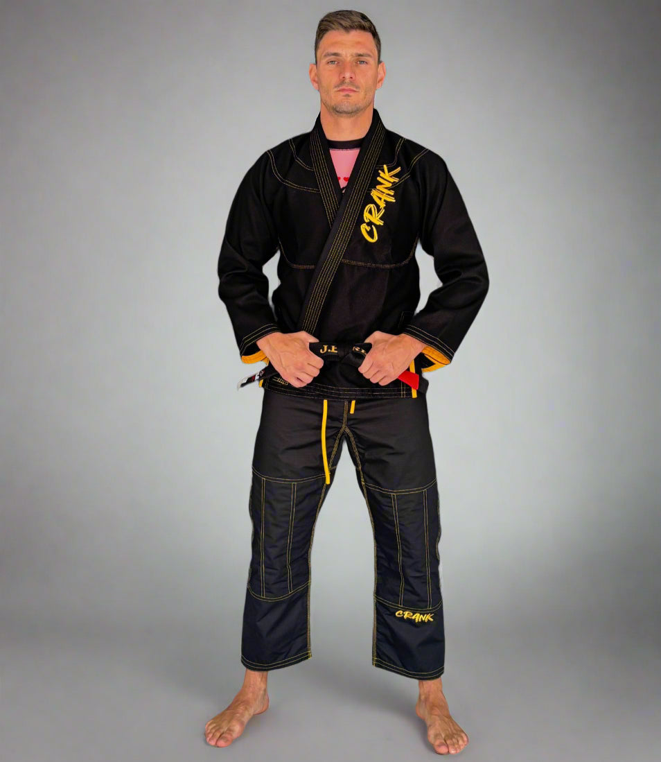 Person wearing a black martial arts uniform with visible branding against a gray wall.