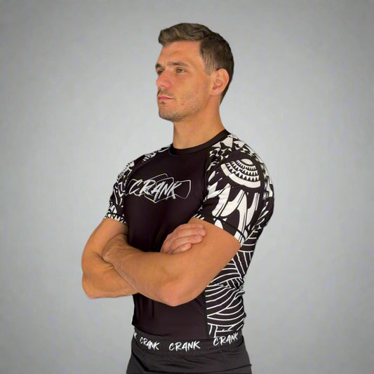 Man wearing a black and white athletic outfit with 'Crank' branding against a gray wall.