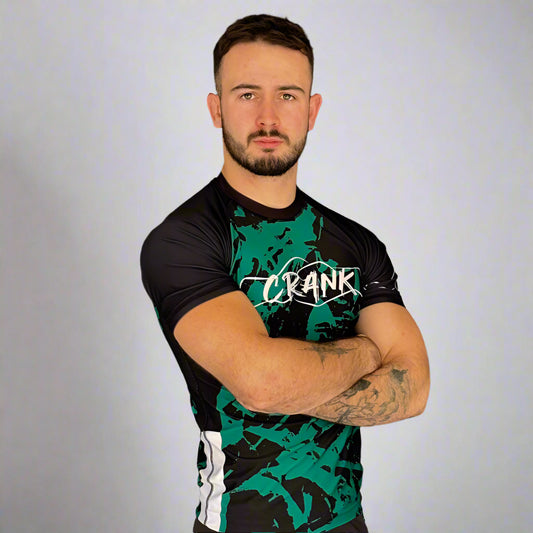 Man wearing a black and green 'Crank' branded outfit standing against a gray wall.